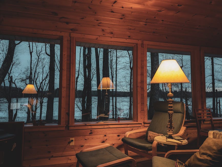 Warm, peaceful cabin interior with glowing lights and lake view, perfect for relaxation and nature enjoyment.