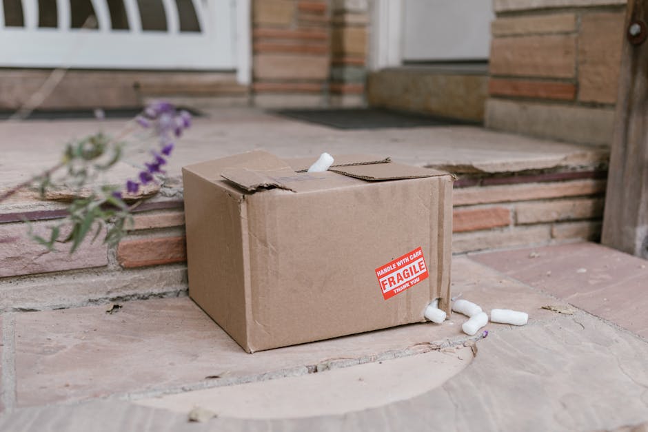 Damaged cardboard package with fragile sticker on porch steps with foam peanuts.