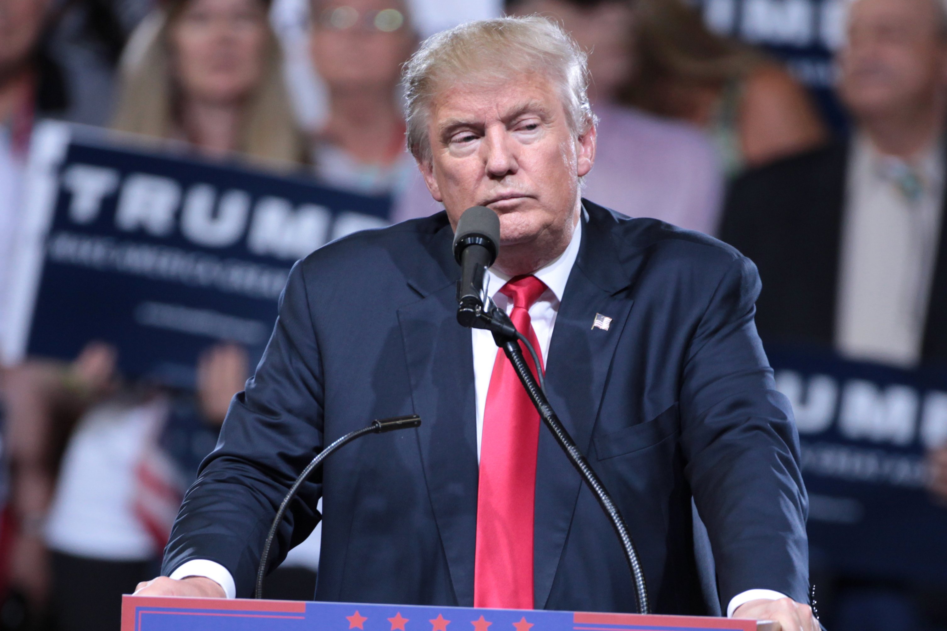 Donald Trump speaking at a campaign event behind a microphone.