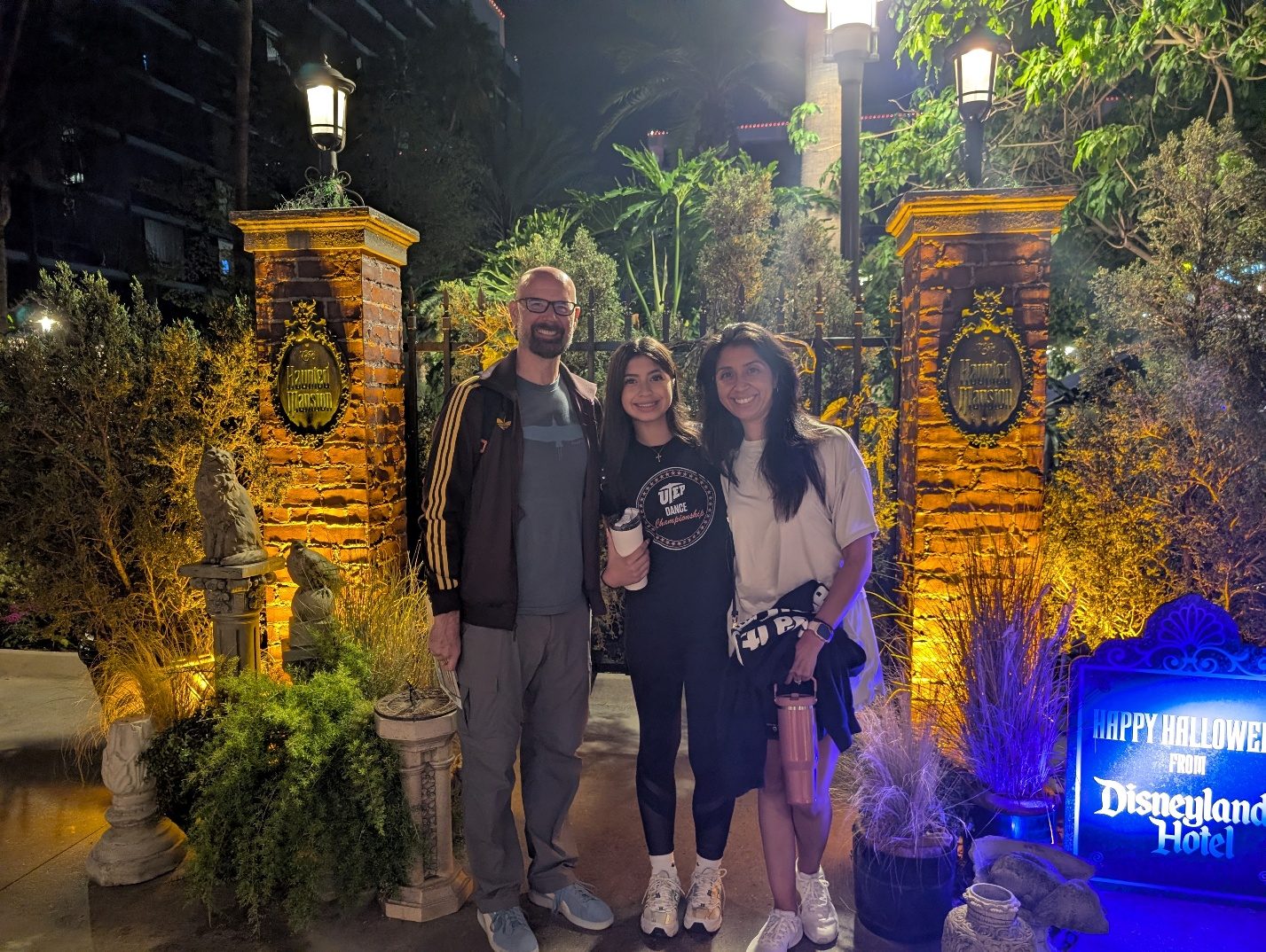 Family posing by Disneyland Hotel Halloween decorations at night.