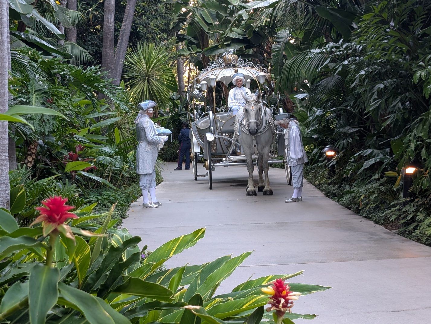 White carriage and statues in a garden walkway.