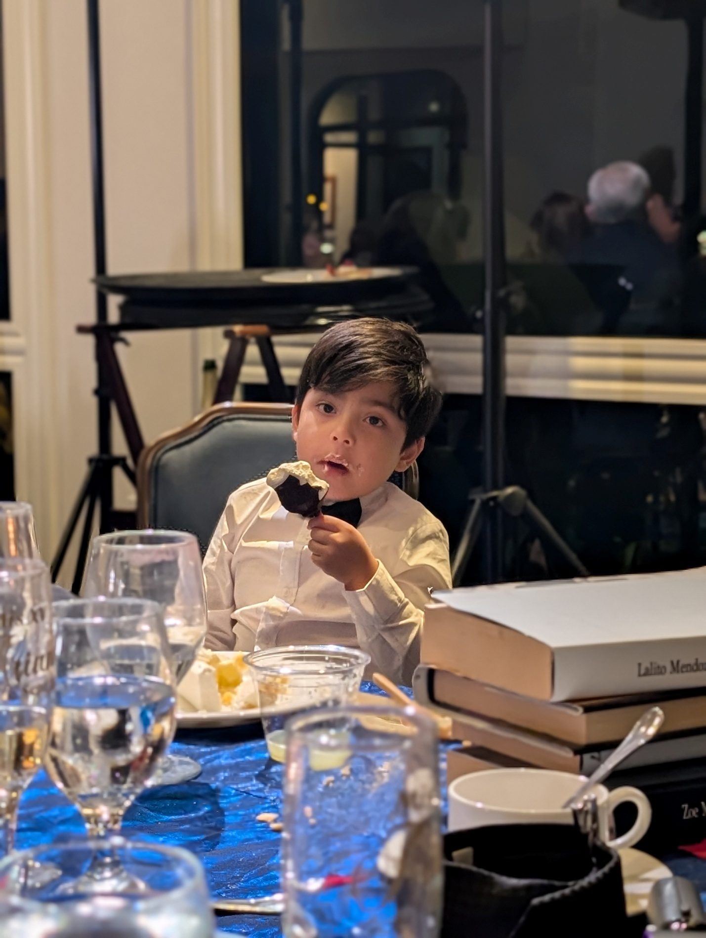 Child sitting at a party table with dessert.