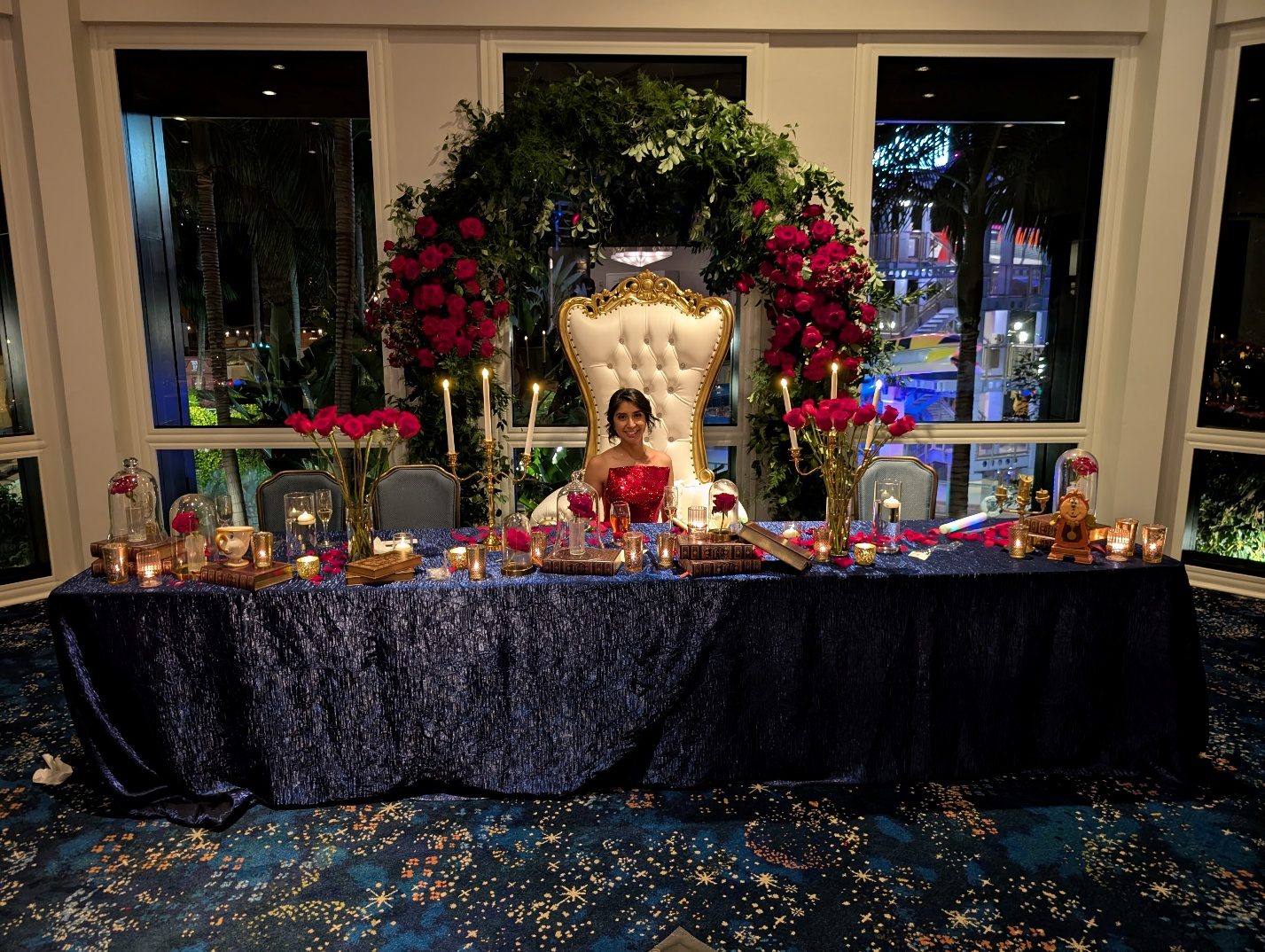 Decorated quinceañera main table with floral arch and gold chair.