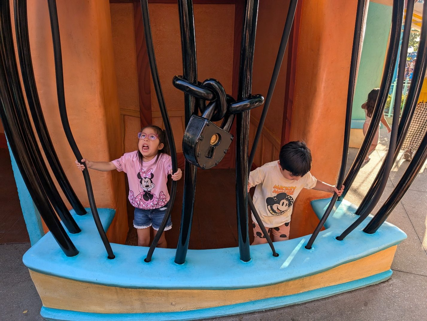 Children posing behind cartoon jail bars.