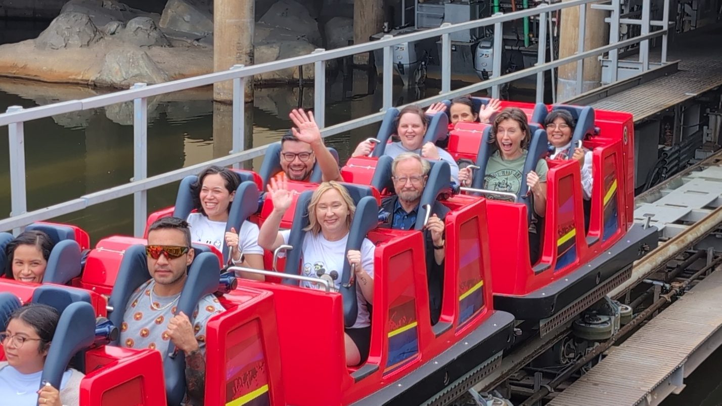 Family riding a red coaster train.