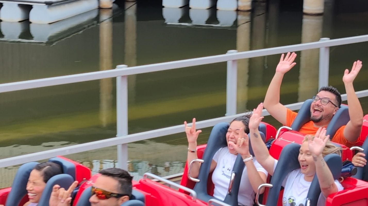 Family waving on a red coaster train.