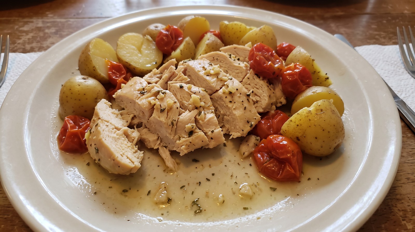 Sliced lemon-herb chicken breast with baby yellow potatoes and cherry tomatoes in light garlic-herb cooking juices
