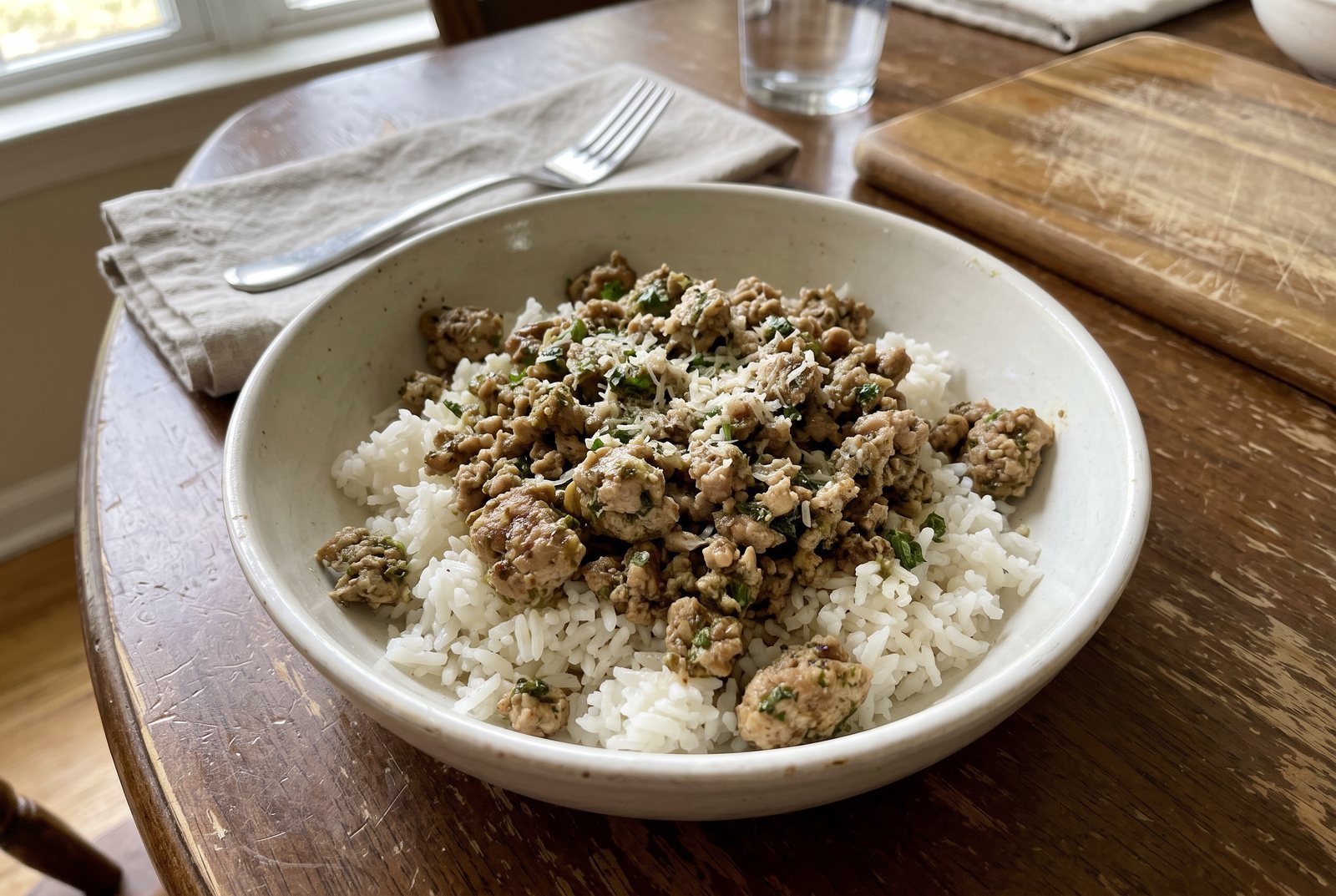 Pesto ground turkey served over white rice with grated Parmesan in a white bowl
