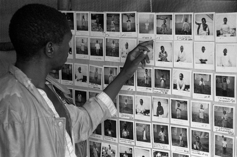 A person looking at rows of photographs connected to the 1994 Rwandan genocide.
