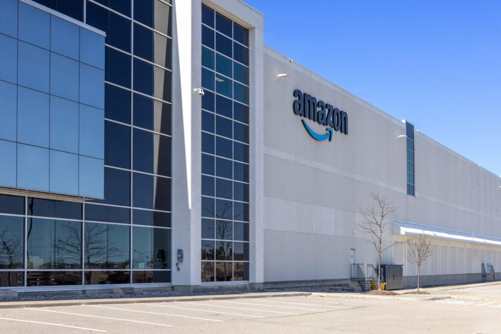 Wide exterior view of an Amazon fulfillment center beneath a clear blue sky.