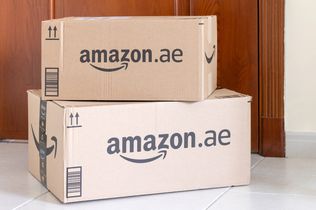 Two Amazon delivery boxes stacked in front of a wooden door.