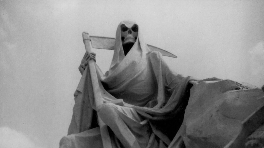 A hooded Grim Reaper sculpture holding a scythe above a rocky landscape.