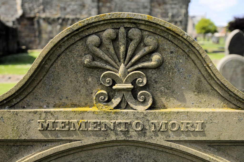 A gravestone carved with bones and the words Memento Mori.